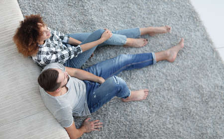 newlywed couple sitting on a carpet in a new living roomの写真素材