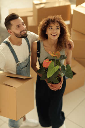 Beautiful young couple is carrying boxes to a new home.