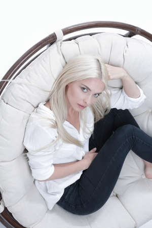 Closeup of a beautiful sad young woman sitting in a large comfortable armchairの写真素材