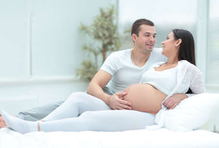 Pregnant woman with her husband relaxing at homeの写真素材