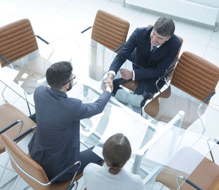 Handshake across the table of financial partners