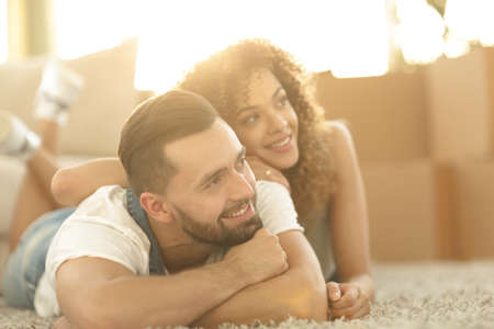 Happy couple lying on the carpet on the blurred backgroundの写真素材