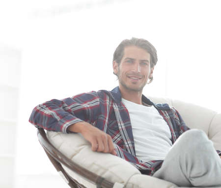close-up of a smiling guy stroking his dog while sitting in a large armchair.の写真素材