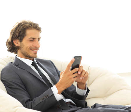 successful business man with a smartphone sitting in a comfortable chairの写真素材