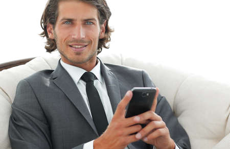 successful business man with a smartphone sitting in a comfortable chair