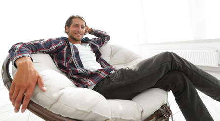 serious guy rests sitting in a large comfortable chair. side view.の写真素材