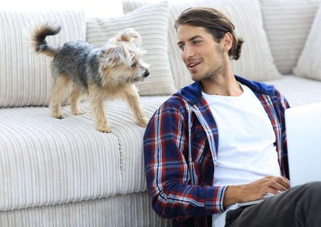 successful guy and his pet in a cozy living room.の写真素材
