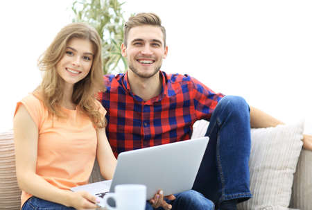 young couple of students uses a laptop sitting on sofaの写真素材