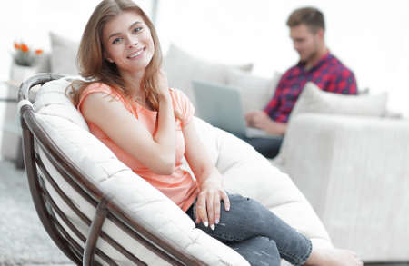 beautiful young woman sitting in a large comfortable chairの写真素材