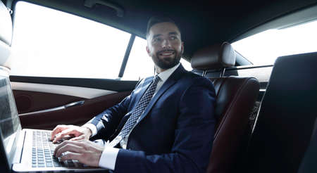 businessman with laptop sitting in the back seat of a carの写真素材