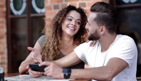 Happy loving  couple using a smartphone sitting in terraceの写真素材