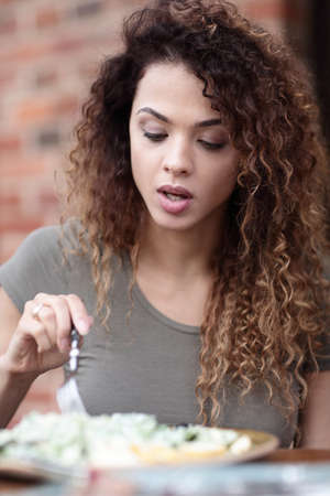 Young woman enjoying food at a street cafe in the hot summer sunの写真素材