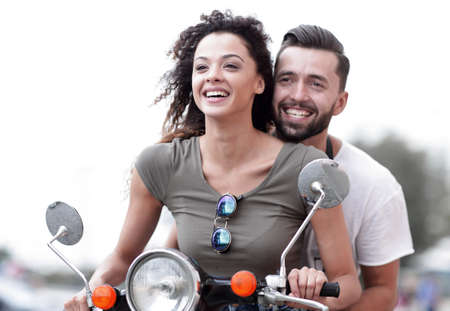 Attractive couple riding a scooter on a sunny day in the cityの写真素材