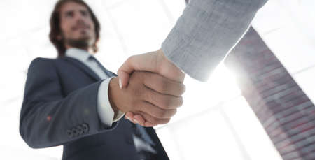 Excited smiling businessman handshaking partner at meeting,