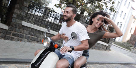 Young couple riding motor scooter in cityの写真素材