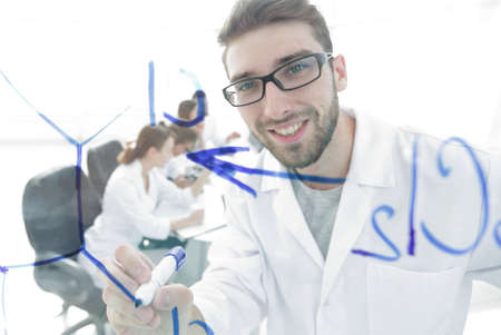 from behind the glass.scientist writes a marker on a glass Board.