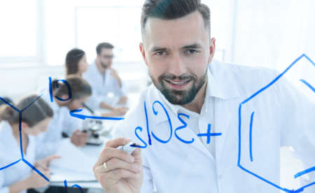 close up of a smiling scientist writes a formula on the blackboardの写真素材