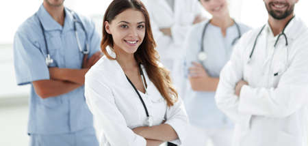 Attractive female doctor with medical stethoscope in front of medical groupの写真素材