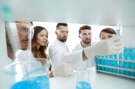 background image is a group of microbiologists studying the liquid in the glass tube.の写真素材