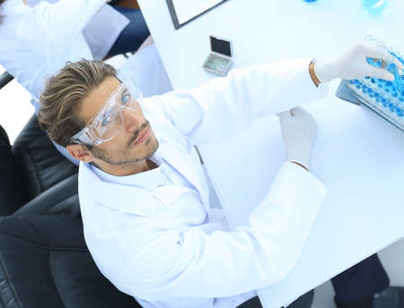 Scientists working with a microscope and make notes in the workplaceの写真素材