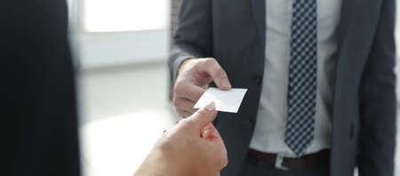 Close-up of two businesspeople exchanging visiting cardの写真素材