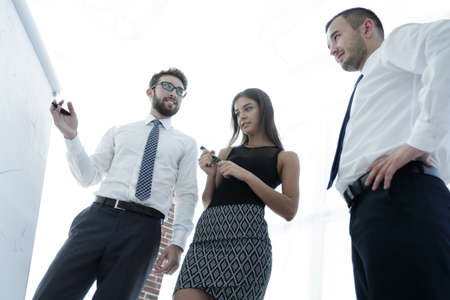 business man showing something on a whiteboard to his colleaguesの写真素材