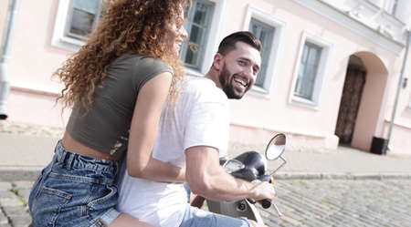 Happy young couple having fun on a scooterの写真素材