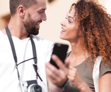 Smiling couple using smart phone together in city