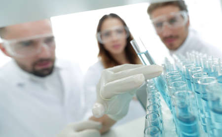 background image is a group of scientists studying the liquid in the glass tube.の写真素材