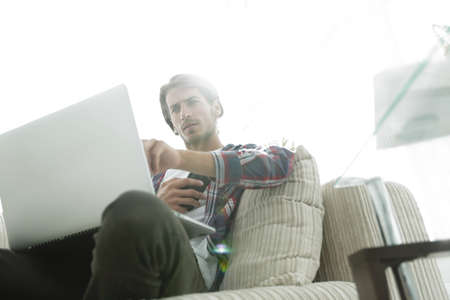 photo young guy with smartphone sitting in a chair. on a blurry backgroundの写真素材