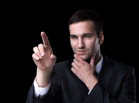 Business man pushing the imaginary  button. Isoladed on black.の写真素材