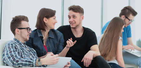 couple of University students sitting on a sofa with friends in