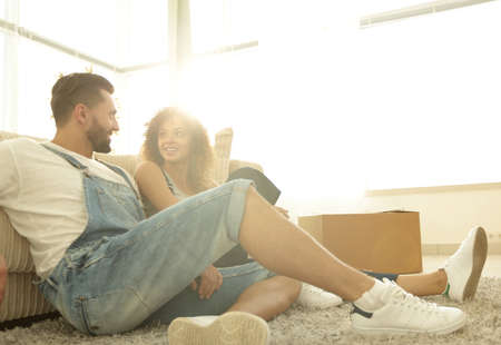 Happy married couple sitting on the carpet in a new apartment.の写真素材