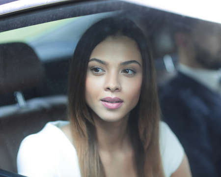Portrait of a woman in a white dress in her car in the back seat