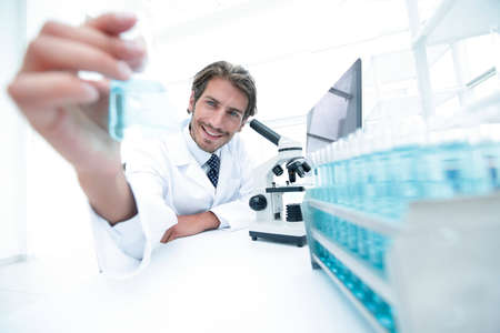 Portrait of a chemist holding a tube with liquid.