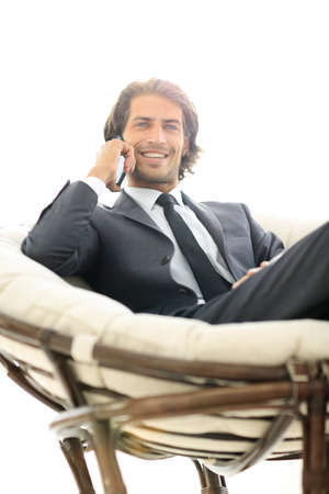 business man talking on a smartphone while sitting in a comfortable chair.の写真素材