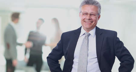 Happy mature business man looking at camera with satisfaction at officeの写真素材