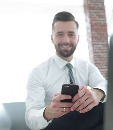 businessman holding a smartphone and looking at the cameraの写真素材