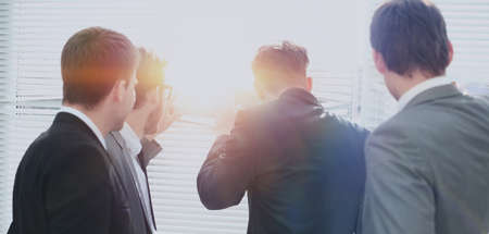 Business team looking through the office window, view from the backの写真素材