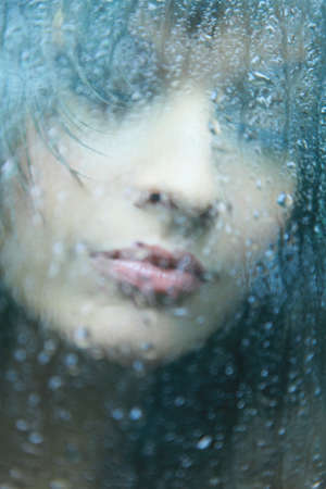 Attractive woman looking out of the window on rainy dayの写真素材