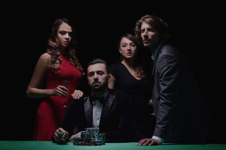 People standing at the table, looking, while a person is bettingの写真素材