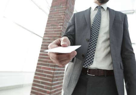 Businessman giving a card. Close-up photo in loft officeの写真素材