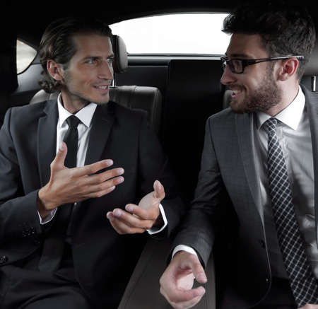 two businessman talking while sitting in the carの写真素材