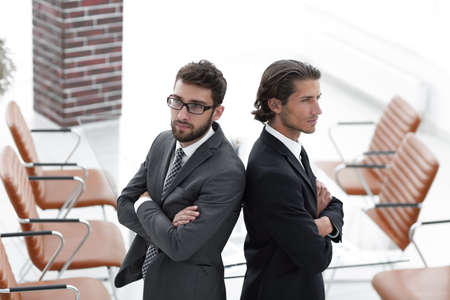 Two men standing back to back and support each other