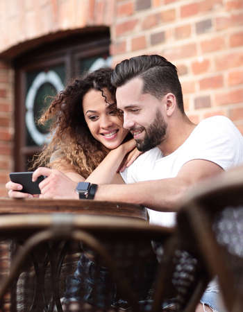 Happy loving  couple using a smartphone sitting in terraceの写真素材