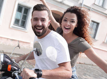 Cheerful young couple riding a scooter and having funの写真素材