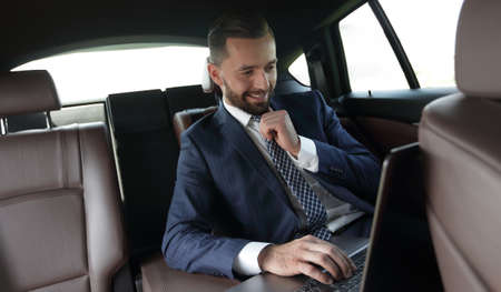 businessman reads information on laptop while sitting in carの写真素材