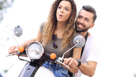 Attractive couple riding a scooter on a sunny day in the city