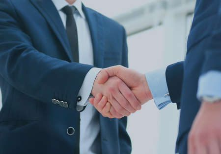 Business colleagues sitting at a table during a meeting with two male executives shaking handsの写真素材