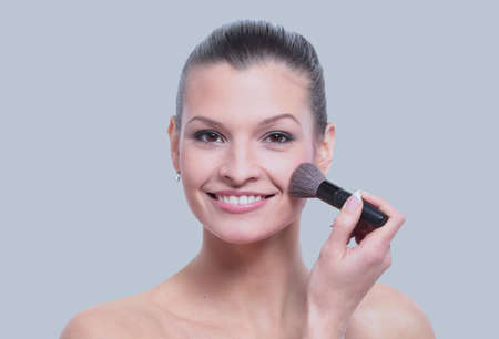 Woman applying dry cosmetic tonal foundation on the face using m